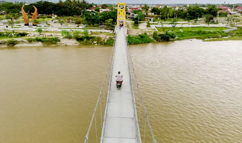 Pengendara sepeda motor melintas di jembatan gantung Tinggede-Kalukubula, Selasa (15/7/2025). (bmzIMAGES/basri marzuki)