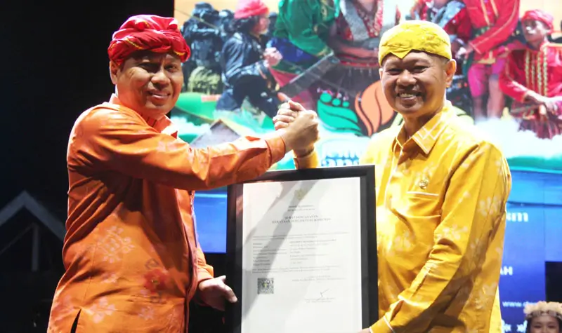 Kakanwil Kemenkum Sulteng Rakhmat Renaldy (kiri) menyerahkan sertifikat Kekayaan Intelektual Komunal untuk tradisi Mentimbe kepada Bupati Sigi, Moh Rizal Intjenae pad apembukaan Festival Danau Lindu 2025 di Desa Tomad, Lindu, Sigi, Jumat (18/7/2025). (@Kemenkum Sulteng)