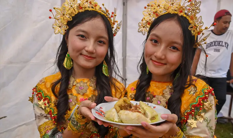 Dua remaja putri menunjukkan makanan tradisional Utadada pada festival Utadada di RTH Asmaul Husna, Binangga, Marawola, Sigi, Sabtu (20/9/2025). (©bmzIMAGES/basri marzuki)